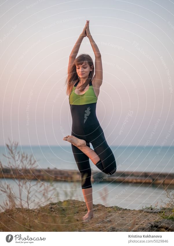 junge Frau im Badeanzug übt Yoga auf erstaunliche Sonnenaufgang. Fitness, Sport, Yoga und gesunden Lebensstil Konzept. Mädchen tun eine Brücke auf Felsen im Meer.