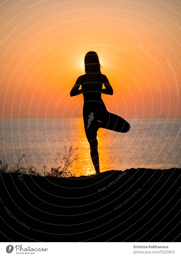 Silhouette junge Frau übt Yoga am Strand über dem Meer auf erstaunliche Sonnenuntergang. Fitness, Sport, Yoga und gesunden Lebensstil Konzept Natur