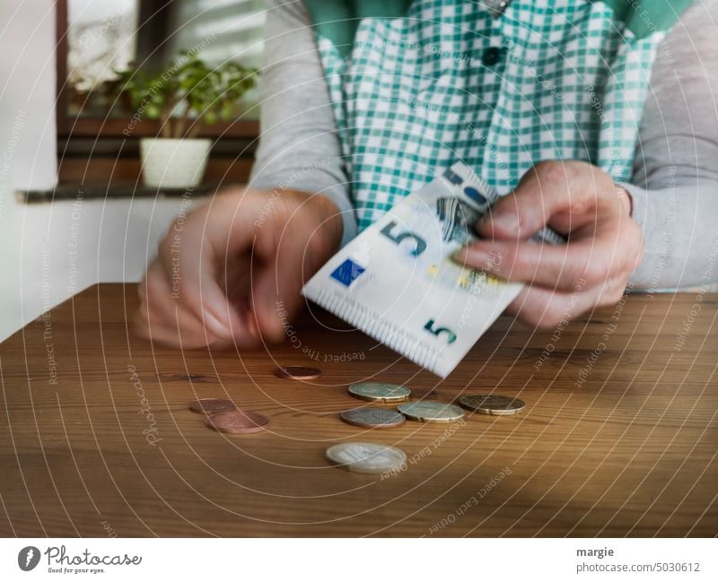 Eine Hausfrau zählt ihr Geld Rentnerin zählen Armut Finanzen sparen Bargeld Münzen Geldmünzen Euro bezahlen Cent Hand Nahaufnahme Zahlung Kittelschürze