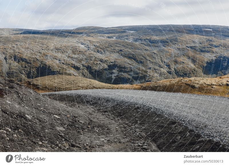 Schotterstraße in norwegischer Berglandschaft Straße Weg Kurve Schwung aufwärts karg öde leer kalt wolkig skandinavisch Landschaft Ausflug Route Fahrbahn