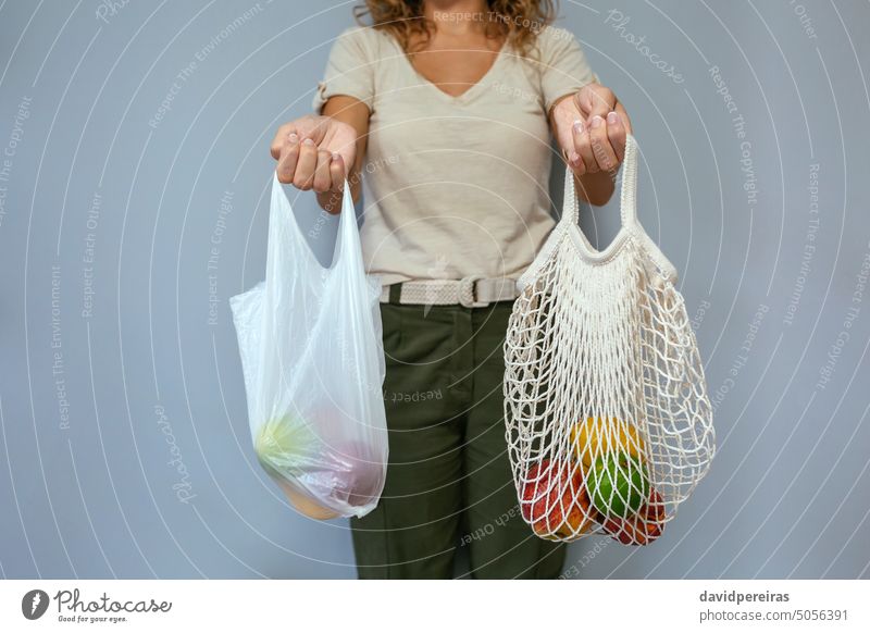 Unbekannte Frau vergleicht wiederverwendbare Netztasche und Einwegplastiktasche mit Obst unkenntlich gesichtslos Beteiligung Vergleich Gegenüberstellung Tasche