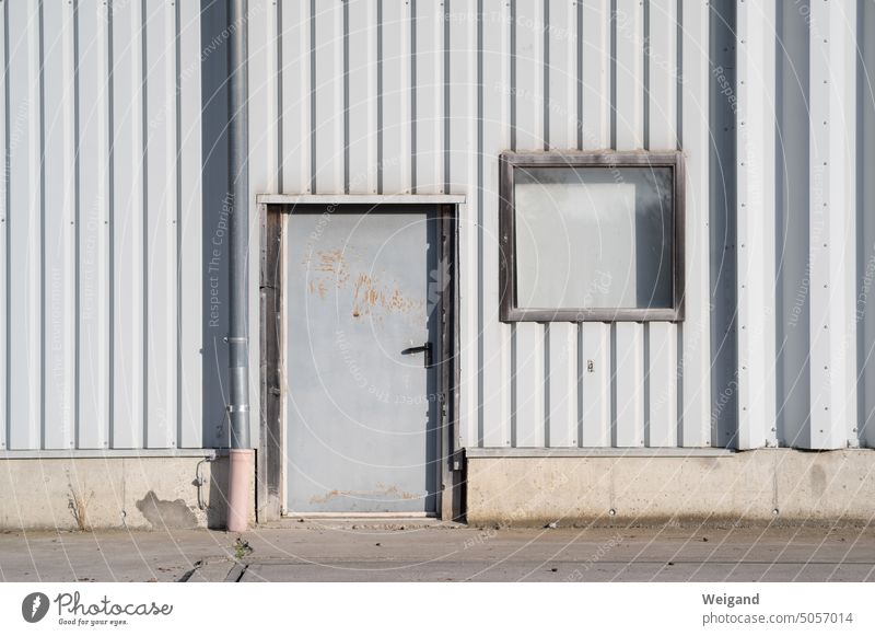 graue Tür in Fabrikgebäude Fabrikhalle Lagerhalle Architektur Industrieanlage Fassade Wand trist Gebäude