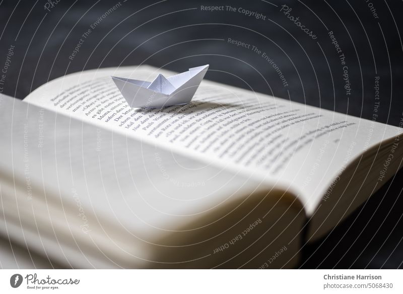 Papierboot auf Buchseite lesen Literatur Bildung lernen Bibliothek Roman Bücher Lesestoff durchsuchen zu Hause Page blättern imagination Fantasiereise