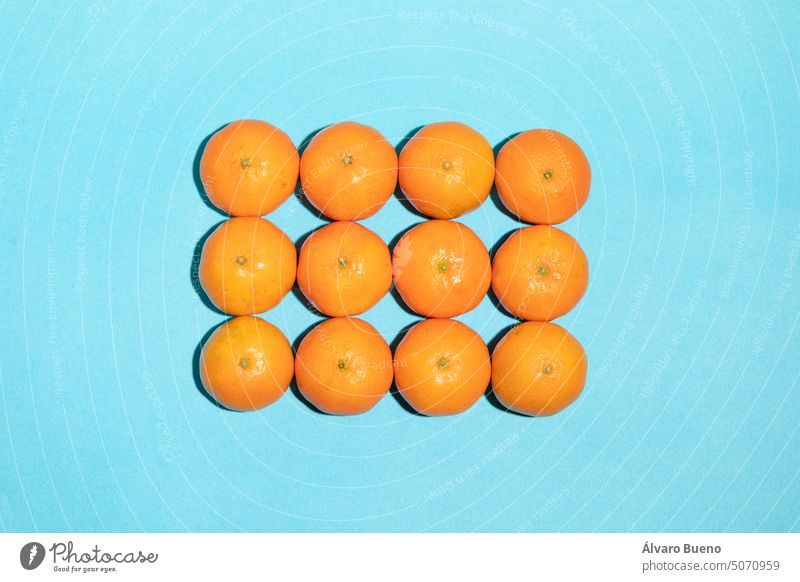 Saftige und natürlich angeordnete Mandarinen in Form eines Rechtecks Früchte Vitamin C Hintergrund blau Textur Reihen Spalten regelwidrig Konzept