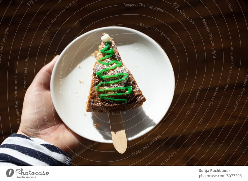 Eine Hand hält einen Teller mit einem Stück Kuchen. Weihnachten. Weihnachten & Advent backen süß Lebensmittel Zuckerguß verziert Feste & Feiern Feiertag Dessert