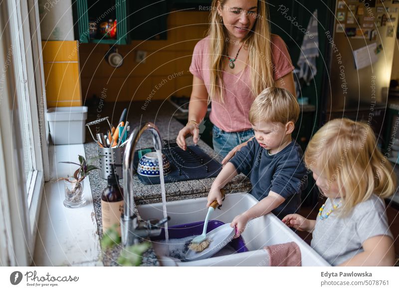 Kinder helfen der Mutter beim Abwasch in der Küche reales Leben echte Menschen Bonden Familie im Innenbereich qualitätsvolle Zeit Haus Kindererziehung Genuss