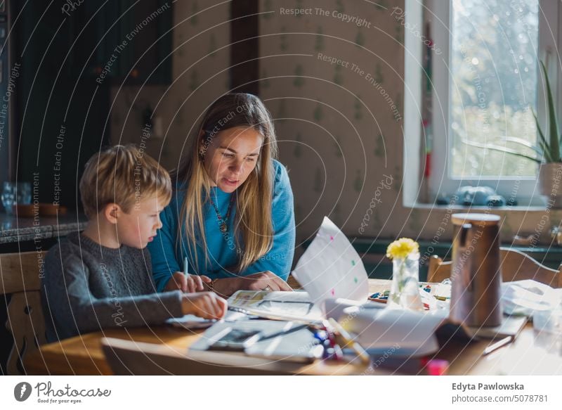 Mutter hilft Sohn bei den Hausaufgaben zu Hause reales Leben echte Menschen Bonden Familie im Innenbereich qualitätsvolle Zeit Kindererziehung Genuss Tag