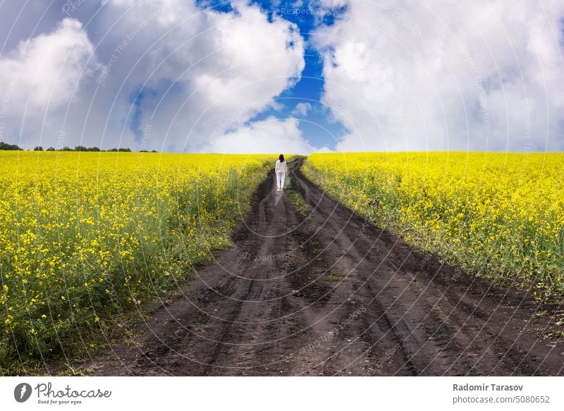 Frau steht auf einem unbefestigten Weg in einem Rapsfeld schön Straße Sibirien Russland Sommer Saison Mädchen gelb Natur Schönheit Kaukasier Glück sonnig Tracht