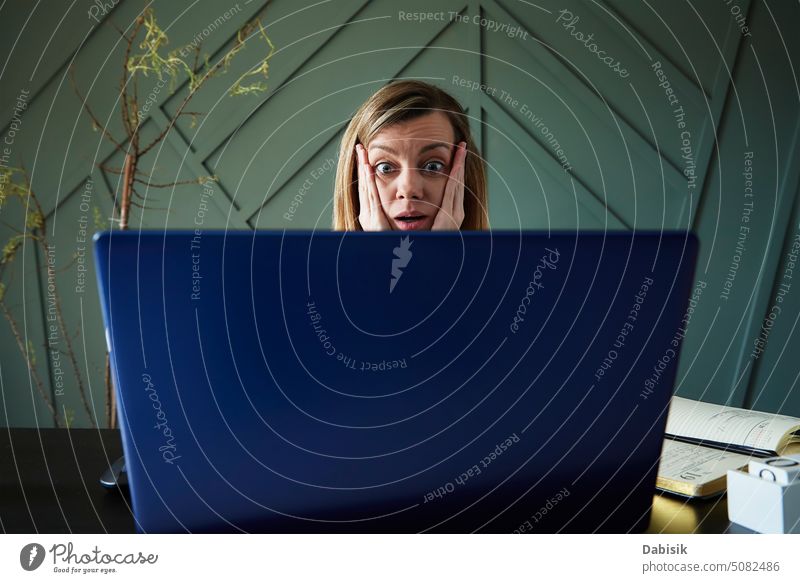 Schockierte Frau schaut auf den Laptop-Bildschirm Emotion Überraschung aufgeregt schockiert online emotionale Reaktion heimwärts Problematik große Augen Tisch
