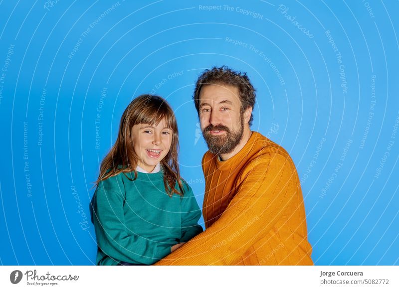 Familienporträt Vater und 6 Jahre alte Tochter. zeigt Glück auf isolierten blauen Studio Hintergrund. Vatertag Elternschaft Kindheit Konzept Papa vereinzelt