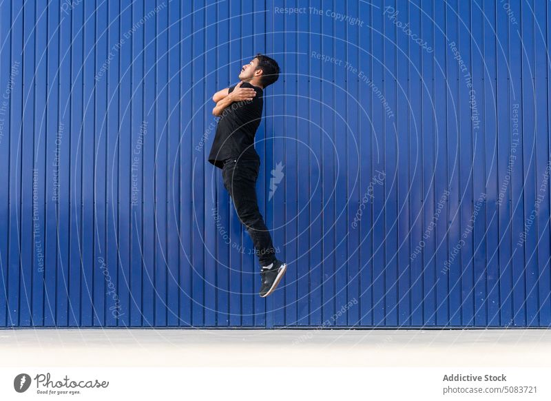 Mann springt gegen blauen Zaun springen Umarmen Schulter Gleichgewicht aktiv schweben üben Tänzer Energie ausführen sich[Akk] bewegen Talent Konzentration