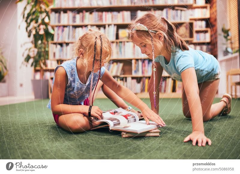 Zwei Schülerinnen lesen Bücher in der Schulbibliothek. Grundschüler, die aus Büchern lernen. Schüler machen Hausaufgaben. Kinder haben Spaß im Schulclub. Zurück zur Schule