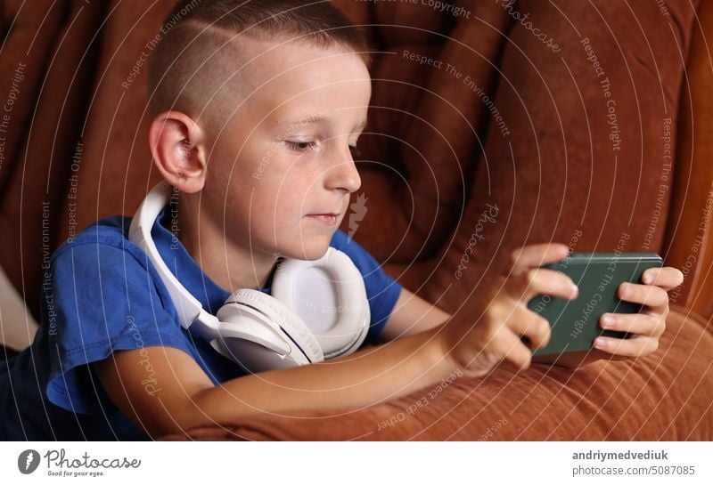 Nahaufnahme von Kind Junge spielt Videospiele In Smartphone zu Hause auf der Couch. Kid mit Telefon für Gaming Online-Bildung Social Media. Schuljunge studiert Spiel auf dem Mobiltelefon.