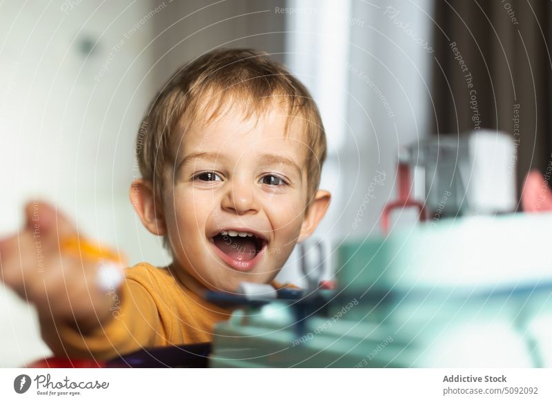 Glücklicher süßer Junge spielt mit Spielzeug zu Hause Kind spielen Lächeln heiter Aktivität unterhalten Vorstellungskraft Interesse Windstille wenig froh