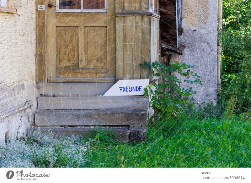 Holztür an einem alten Holzhaus mit einem Schild mit deutschem Text: Freunde Einladung Sprichwort Gebäude Textfreiraum Tür Eingang lustig Deutsch Haus niemand