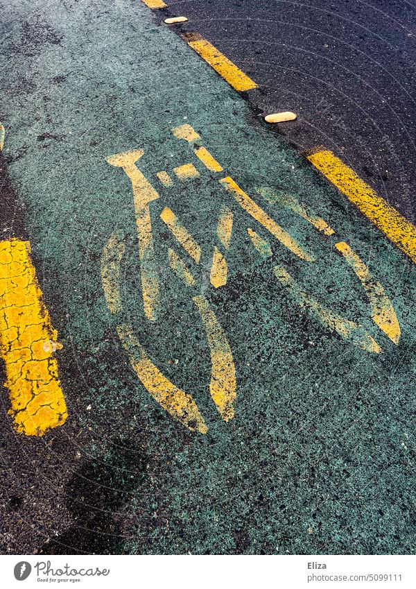 Gelbes Fahrradsymbol auf Fahrradweg auf der Straße Asphalt Verkehrswege Piktogramm Wege & Pfade Fahrbahnmarkierung gelb dunkel Fahrrad fahren Straßenverkehr