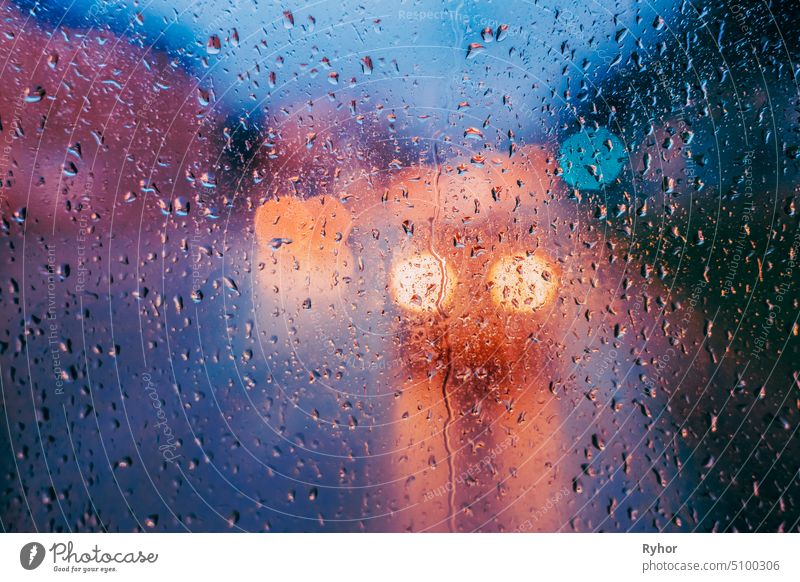 Wassertropfen von Regen auf Glas Hintergrund. Straße Bokeh Lichter aus dem Fokus. Herbst abstrakte Kulisse Konzept texturiert Fenster gelb glühen Unschärfe
