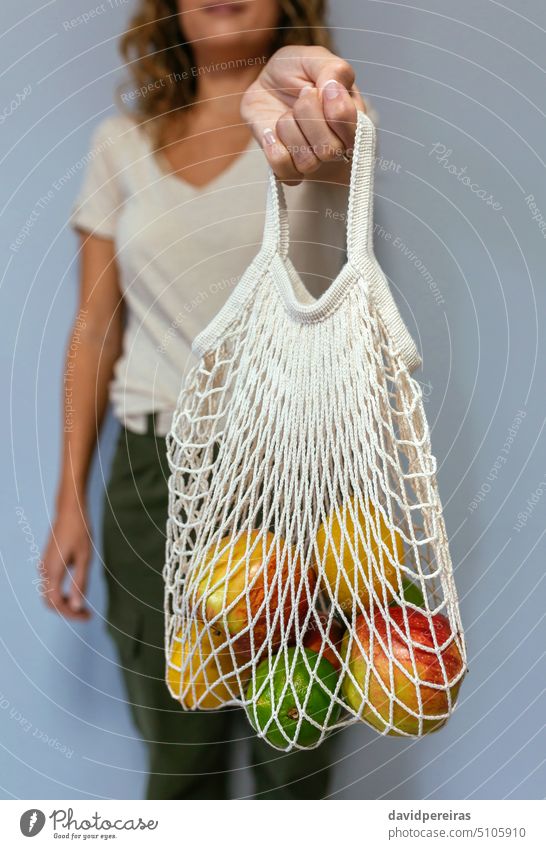 Unbekannte Frau hält wiederverwendbare Netztasche mit Früchten in der Hand unkenntlich gesichtslos Beteiligung zeigend Tasche wiederverwendbare Tasche