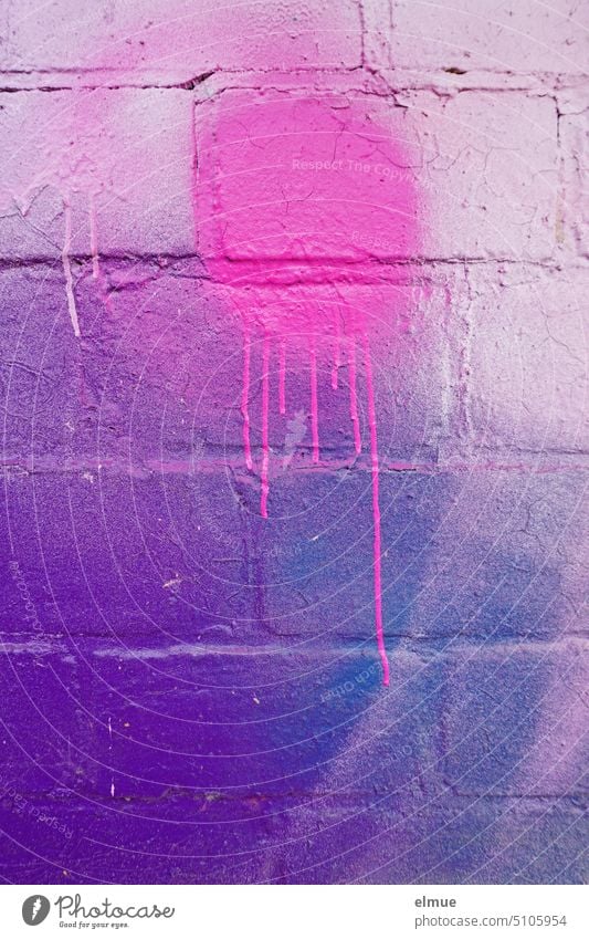 pinkfarbener Klecks mit verlaufender Farbe an einer verschieden farbig angespayten Ziegelwand bunt rosa lila Knallfarben sprayen Schmiererei Graffiti Wand
