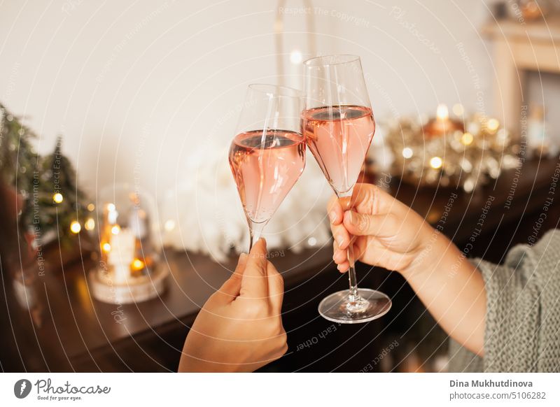 Zwei Gläser Rosensekt in der Hand, um auf Weihnachten oder Neujahr anzustoßen. Feiern auf einer Party. Alles Gute zum Geburtstag oder Jahrestag. Festliche Getränke Hintergrund. Feste und Feiern. Jubel mit Gläsern. Horizontal New Year Party Hintergrund.