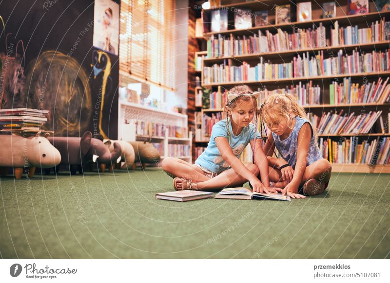 Zwei Grundschüler lesen Bücher in der Schulbibliothek. Schulmädchen lernen aus Büchern. Sie machen Hausaufgaben. Kinder haben Spaß. Zurück zur Schule Rücken