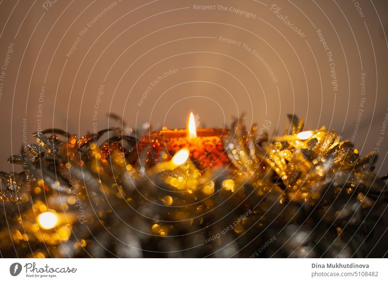 Golden glänzende festliche Kerze mit brennender Flamme als Heimdekoration. Weihnachtsferien Dekoration im Winter. Innenarchitektur Details. golden Hintergrund