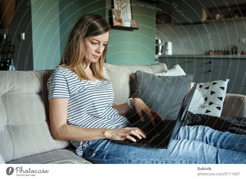 Frau zu Hause am Laptop. Fernarbeit im Heimbüro Freiberufler benutzend heimwärts Büro Arbeit abgelegen Browsen online konzentriert arbeiten Wohnzimmer Liege