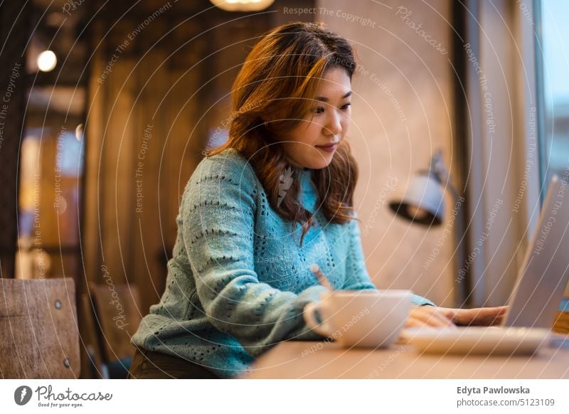 Junge Frau arbeitet an einem Laptop in einem Café echte Menschen offen Mädchen jung Erwachsener Spaß Jahrtausende Jahrtausendgeneration asiatisch Japanisch