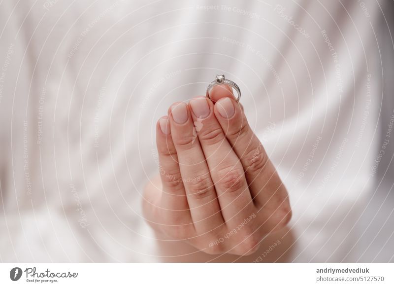 weibliche Hand hält Ehering aus Weißgold und Diamanten auf einem weißen Hintergrund. Luxus teuer Vorschlag Ring. Braut in Hochzeitstag. Accessoire Schmuck