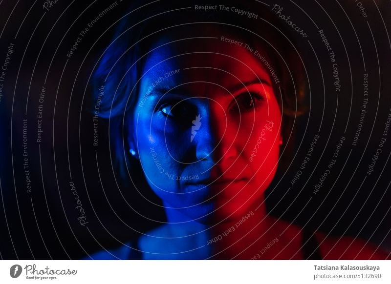 Das Gesicht einer jungen Frau in blauem und rotem Neonlicht auf dunklem Hintergrund neonfarbig Licht dunkel Porträt Neon-Beleuchtung neonfarben beleuchtet