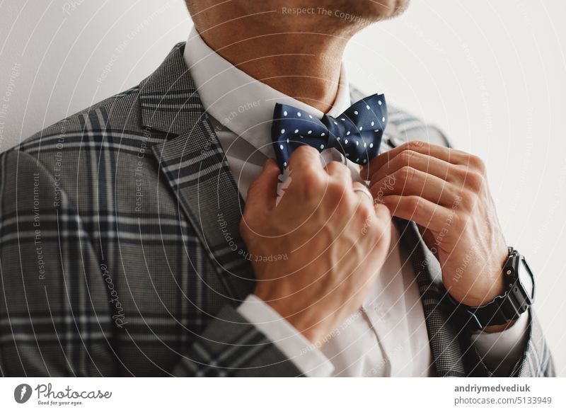 Mann der Bräutigam in einer Hochzeit formale Kostüm mit Schmetterling. Anzug, Hände, Pflege, Krawatte, korrigieren, anpassen, Mode, Bogen. Hübscher Geschäftsmann im Anzug. Porträt eines sexy Mannes