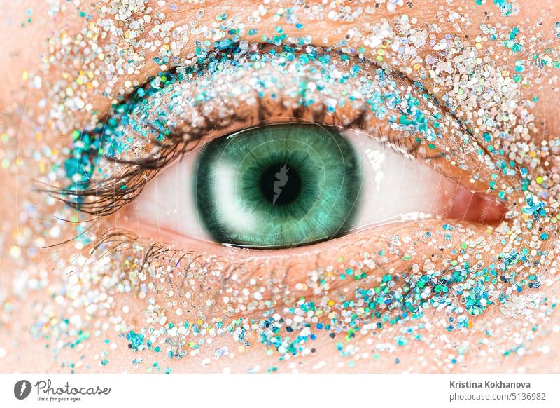 Makro grünes weibliches Auge mit Glitter Lidschatten, bunte Funken, Kristalle. Schönheit Hintergrund, Mode Glamour Make-up-Konzept. Urlaub Abend Make-up Detail.