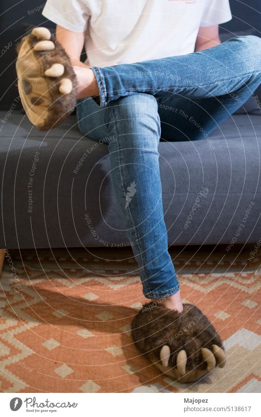 Unbekannter junger Mensch mit Jeans und Bärenklauen-Pantoffeln Hintergrund Party Schuhe Karneval Tracht Glück Sitzen Erwachsener Stil sich[Akk] entspannen