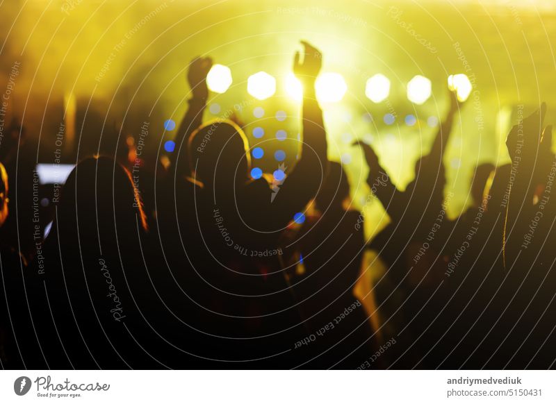 jubelnden Menge vor hellen gelben Bühne Lichter. Silhouette Bild der Menschen tanzen in Disco-Nachtclub oder Konzert bei einem Musikfestival. Beifall spendend
