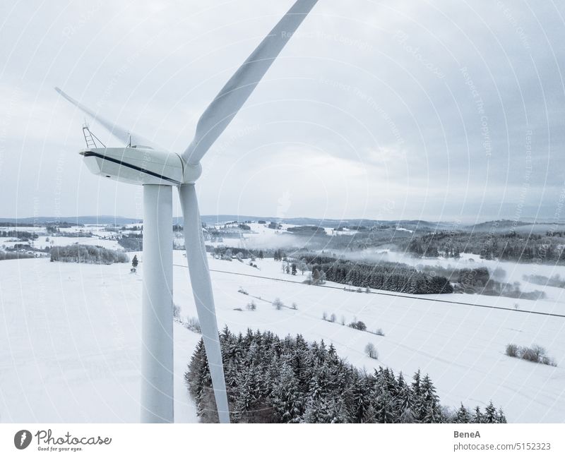 Windkraftanlage in einer verschneiten Winterlandschaft aus der Vogelperspektive Antenne Kohlenstoff Sauberkeit Cleantech Klima Wolken wolkig Stromrichter Land