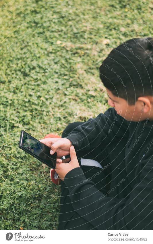 Draufsicht Junge sitzt im Park und schaut auf sein Smartphone, selektiver Fokus Jugendzeit Anruf Selbstvertrauen Anschluss Konnektivität Kontemplation