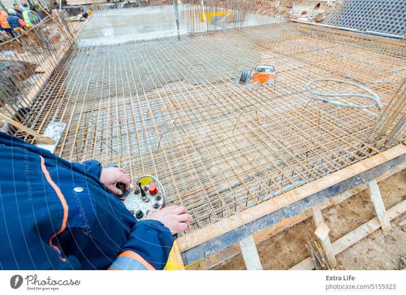 Arbeiter hält eine drahtlose Fernsteuerung für eine Betonpumpe auf einer Baustelle Aktivität beitreten Arme Basis Casting Zement Tiefbau Befehl betonieren