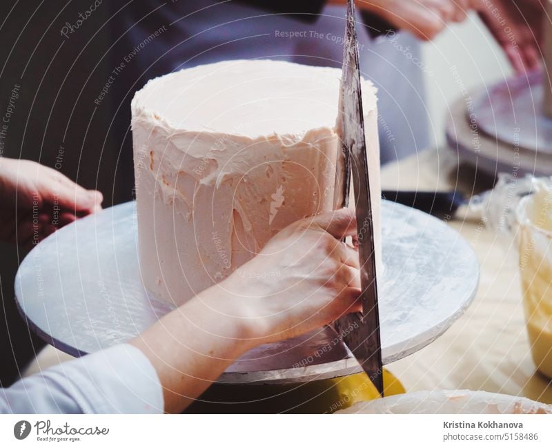 Close Up Of Woman In Bakery Dekorieren Kuchen mit Zuckerguss. Frau die Hand Ebenen Creme auf Mousse, Dekoration Zuckerguß Lebensmittel Dekoration & Verzierung
