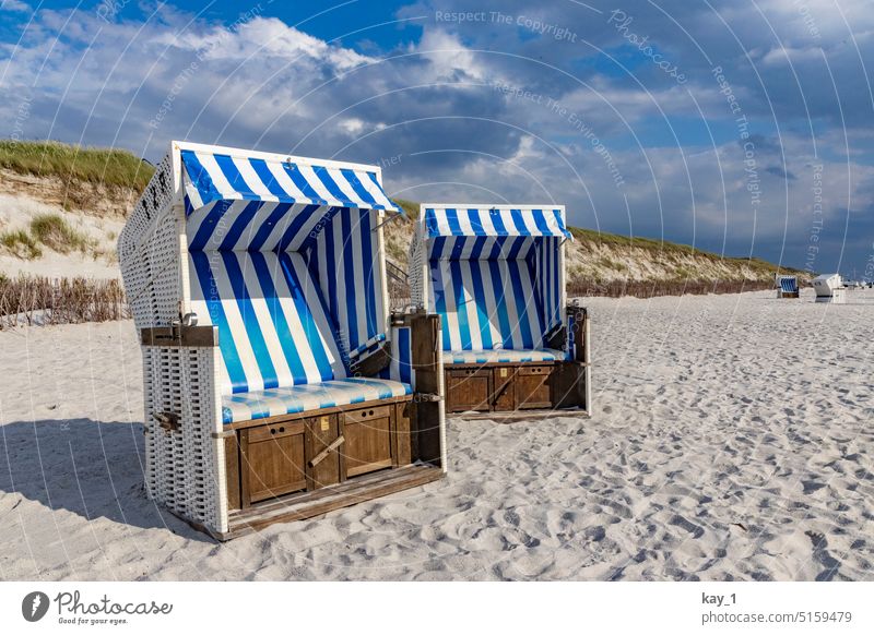 Strandkörbe am Strand mit Düne im Hintergrund Strandkorb Stranddüne Sand Sandstrand Küste Dünengras dünenlandschaft blauweiß Sonnenlicht Sonnenschein