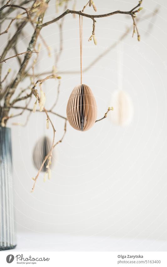 An Zweigen hängende Ostereier an einer weißen Wand. Ostern Papier Ei Ast Dekoration & Verzierung Tisch Vase Tischlandschaft eiförmig Pastell Stubenschmuck