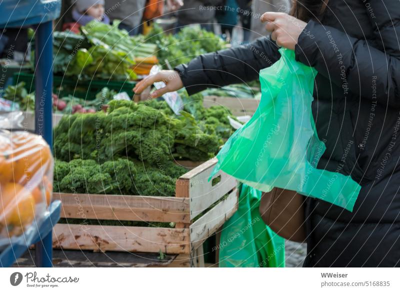 Auf einem Wochenmarkt kauft eine Frau frisches Gemüse und packt es in eine grüne Plastiktüte Markt Gemüsestand Stand kaufen einkaufen einpacken aussuchen Umwelt