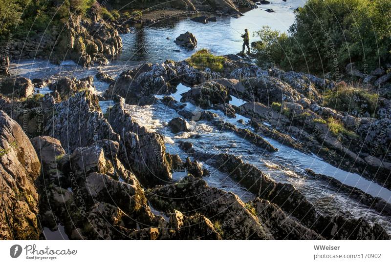 Am wilden kleinen Fluss, der sich durch Felsformationen schlängelt, steht ein Angler im Abendlicht angeln Landschaft Felsen fließen Strukturen natürlich Natur