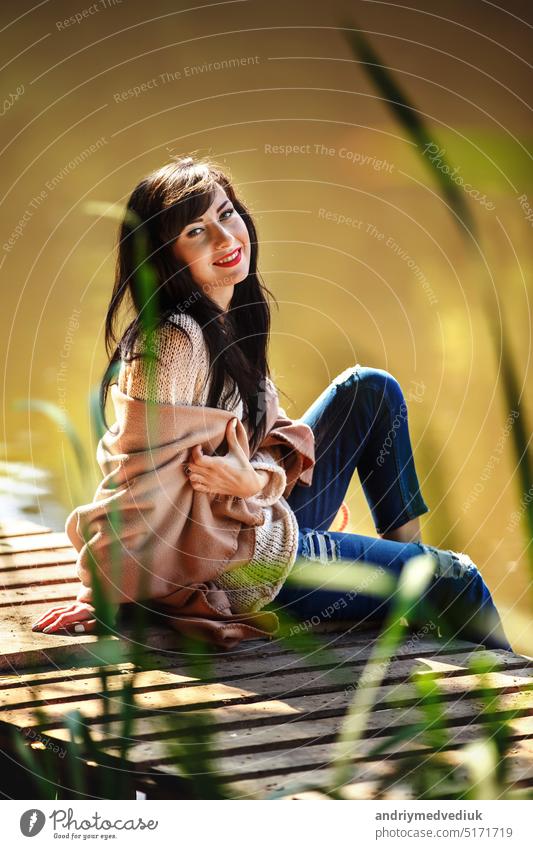 Schönes Mädchen mit langen brünetten Haaren sitzt auf der Brücke. Natur schwarz schön Sommer Himmel Frau farbenfroh Windstille Holzplatte Hintergrund Wald