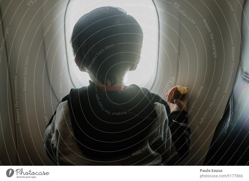 Rückansicht eines Kindes, das durch ein Flugzeugfenster schaut Kindheit Fenster Himmel Ferien & Urlaub & Reisen Luftverkehr Flugzeugausblick Wolken fliegen blau