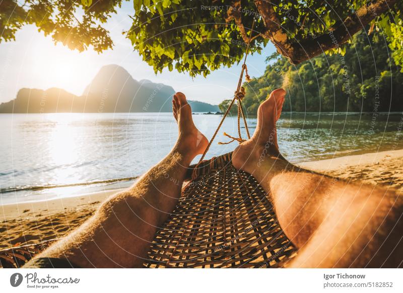Füße eines erwachsenen Mannes, der sich in einer Hängematte am Strand während des Sommerurlaubs entspannt entspannend Fuß Feiertag Asien ruhen romantisch Sand