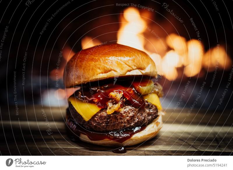 Cheeseburger auf einem Holztisch vor einem Kamin. Amerikaner Hintergrund Speck Barbecue gegrillt grillen Rindfleisch groß Brot Brötchen Burger karamellisiert