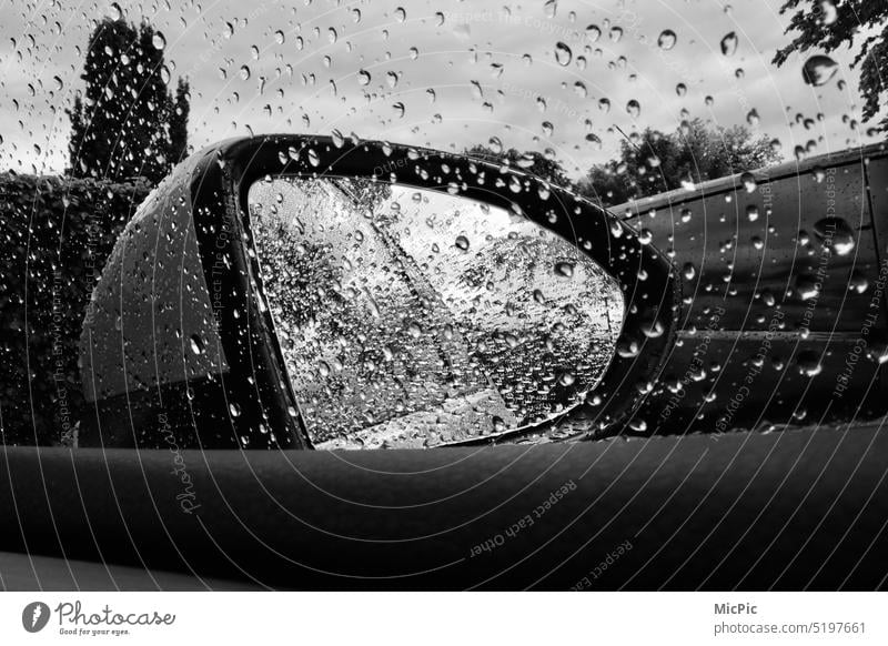 Blick in den Seitenspiegel am Auto bei Regenwetter Regentropfen auf Autoscheibe nasse Scheibe Tropfen Sicherheit Wassertropfen schlechtes Wetter Nahaufnahme