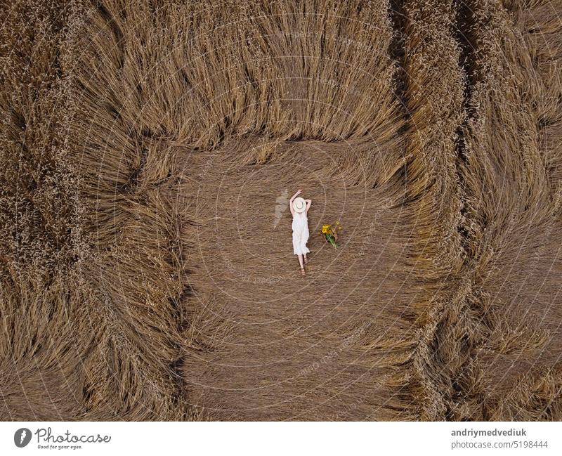 Luftaufnahme einer hübschen jungen Frau, die die Natur genießt. Mädchen im weißen Kleid liegt im Weizenfeld. Menschen, Reisen, Freiheit Konzept. Feld Model