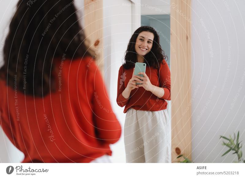 Junge glückliche Frau, die ein Selfie vor dem Spiegel macht jung Glück Lächeln heimwärts Telefon Porträt Handy Smartphone Foto posierend Bekleidung attraktiv