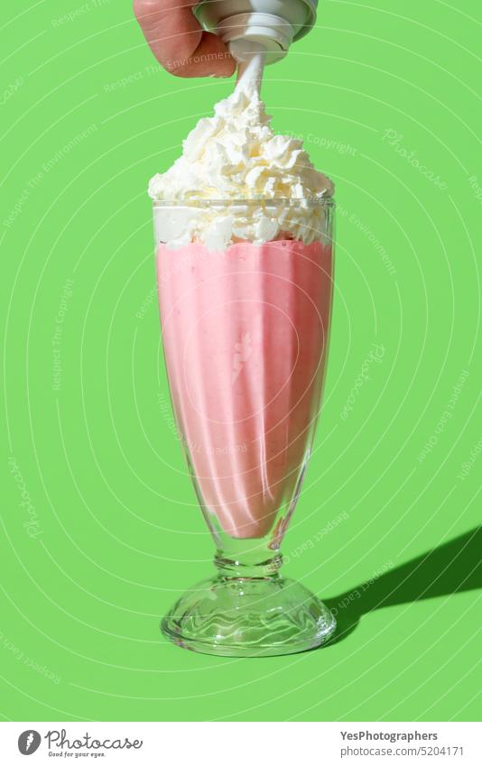 Erdbeermilchshake mit Schlagsahne, minimalistisch auf einem grünen Hintergrund Getränk hell Dose Cocktail kalt Farbe Textfreiraum Sahne Küche Tasse ausschneiden